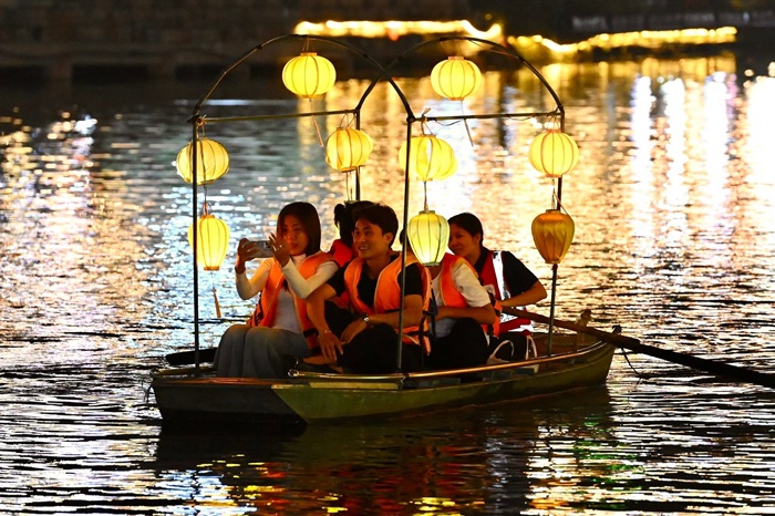 Du khách ngồi trên thuyền ghi lại khoảnh khắc không gian lên đèn ở hồ Kỳ Lân - Ảnh: Fanpage Phố cổ Hoa Lư - Ninh Bình